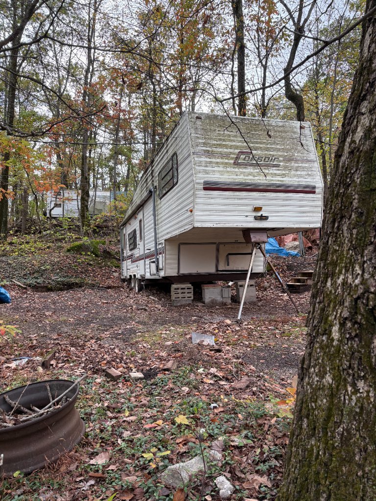 Fifth-wheel camper in a wooded location